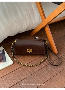 Close-up of brown polished leather square bag with gold twist lock and chain strap