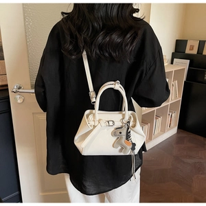 Rear view of a white leather crossbody bag with a horse charm and slim shoulder strap