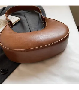 Detailed close-up of brown crescent hobo bag featuring premium leather texture and silver buckle