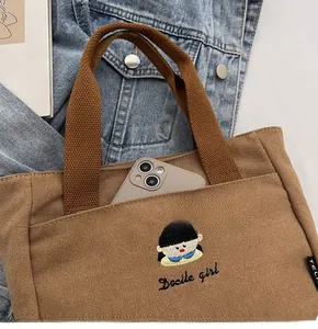 Vue détaillée du sac en toile marron avec poche pour téléphone et broderie