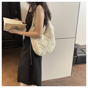 Close-up of beige crochet shoulder bag showing intricate hollow geometric knit patterns