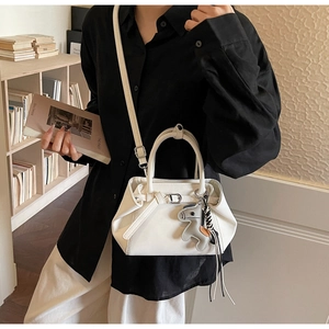 Detail of white PU leather handbag with horse charm shown in a lifestyle model setting