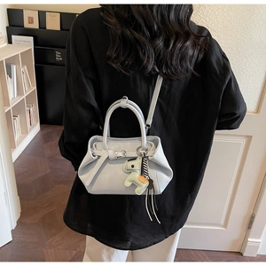Detail of light blue crossbody bag featuring a belt buckle and green horse charm