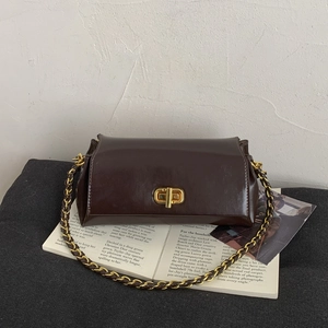 Detail of dark brown glossy leather handbag with gold twist lock and chain strap
