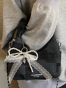 Stylish dumpling bag with lace bow and pearl details shown on a grey hoodie