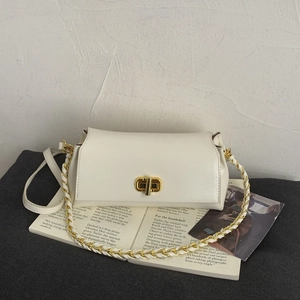 Detailed view of cream leather square bag with gold twist lock on a fashion magazine