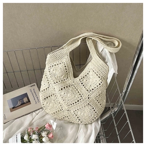Detail of hand-crocheted hollow floral pattern on a cream woven beach tote bag