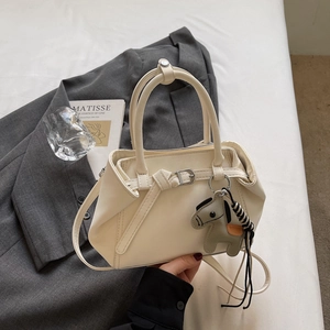 Detailed view of a beige leather tote with top handles and a green horse charm