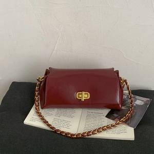 Close-up of vintage burgundy leather shoulder bag with gold twist lock and woven chain strap