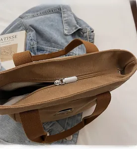 Vue détaillée de la fermeture éclair en métal argenté sur le sac fourre-tout en toile marron