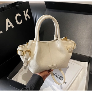 Détail macro du sac seau en cuir grainé blanc cassé avec garnitures dorées chic