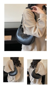 Detail shot of black crescent shoulder bag with smooth faux leather texture and zipper