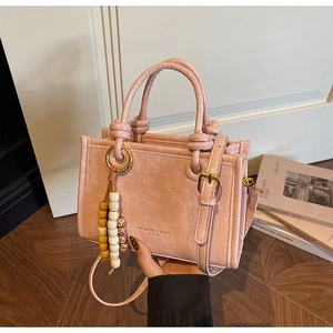 Pink patent leather crossbody bag with crinkled texture and colorful bead charm decoration