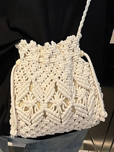 Minimalist hand-woven straw bucket bag with drawstring and stylish crossbody strap