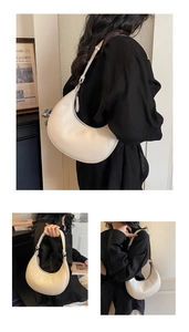 Detailed view of cream crescent bag featuring lychee grain leather and adjustable strap
