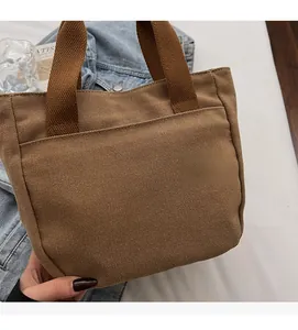 Vue détaillée de la texture du sac en toile marron avec poignée renforcée et poche frontale