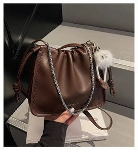 Détail du sac seau en cuir marron foncé avec design plissé et chaîne argentée