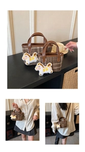 Detail of plaid tote bag featuring fuzzy pony charm and leather trim for crossbody use