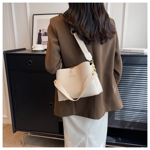 Detail view of cream lychee texture leather bucket bag with gold hardware and wide strap