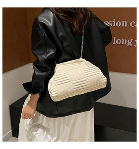Détail d'un sac à bandoulière beige tissé avec motif en losange et fine chaîne métallique