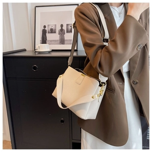 Detail view of cream lychee texture leather handbag with elegant gold metal buckle hardware