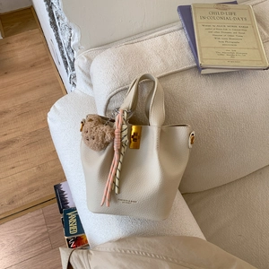 Détail du sac seau en cuir grainé beige avec pendentif ours en peluche et boucles dorées