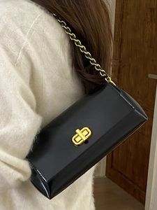 Elegant black patent leather underarm bag with gold chain strap and turn-lock closure
