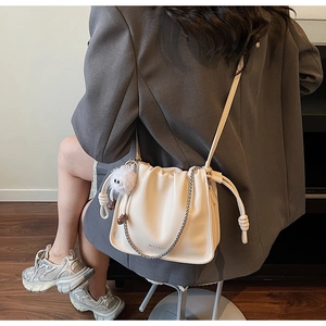 Détail du sac à plis nuage blanc cassé avec chaîne argentée et pompon en peluche