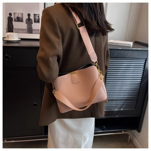 Pink lychee textured bucket bag with wide strap styled on model in urban casual outfit