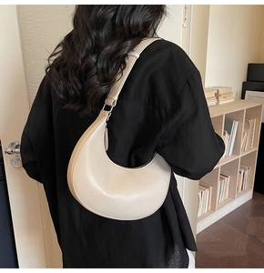 Detail view of a cream minimalist hobo bag worn over the shoulder with adjustable strap