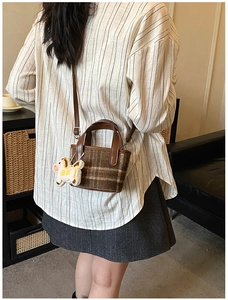 Brown plaid tweed mini tote bag with leather handles and white horse plush charm on model