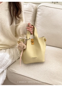Détail du sac seau en cuir jaune clair avec garniture dorée et breloque ours en peluche