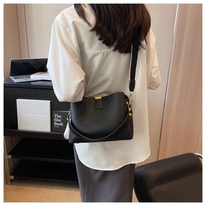 Detail of black pebbled leather bucket bag with wide strap on model in home office