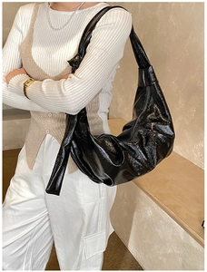 Detail of the knotted shoulder strap on a black pleated crescent hobo bag for women