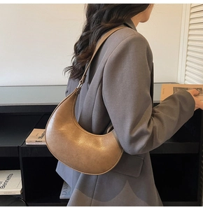 Chic brown leather shoulder bag shown on model with vintage texture and half-moon design