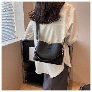 Fashionable black lychee grain bucket bag shown worn by a model in soft indoor lighting