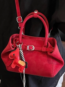 Elegant red suede handbag with horse charm accessory and adjustable silver metal buckle strap
