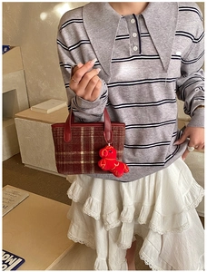 Detail view of a plaid mini tote bag featuring a cute red horse plush charm accessory