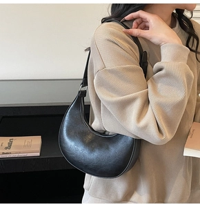 Detail showing black half-moon shoulder bag with lychee texture and silver hardware