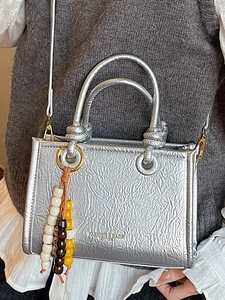 Metallic silver crossbody handbag with wrinkled texture and beaded charm on model
