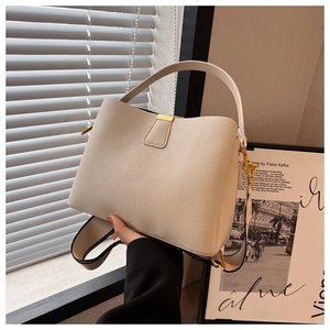 Detail of cream bucket bag showing grainy leather texture and gold square buckle