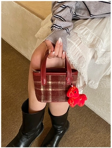 Detail of red and brown plaid mini tote bag featuring a cute horse plush charm