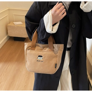 Détail du sac à main en toile kaki avec broderie de dessin animé et poignées en sangle