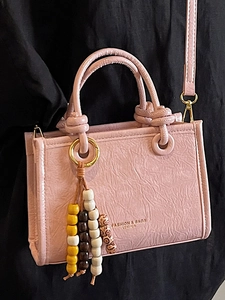 Pink minimalist crossbody bag with wrinkled leather texture and wooden beaded pendant