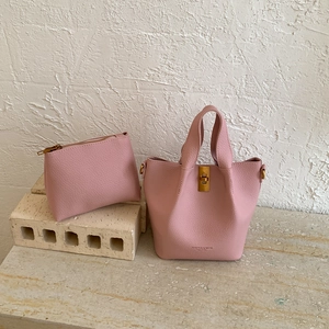 Sac seau en cuir rose à texture litchi avec fermoir rotatif en métal sur marbre