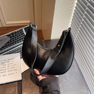 Minimalist black crescent shoulder bag with smooth matte leather texture and silver hardware