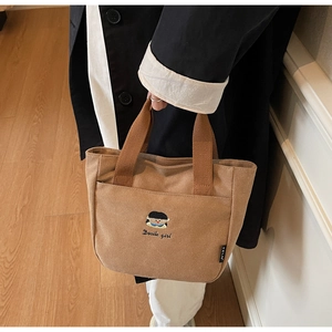 Gros plan détaillé du sac cabas en toile marron avec broderie et poche avant