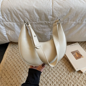 Detail view of a beige crescent underarm bag featuring smooth faux leather and silver metal buckles