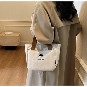 Détail du sac cabas en toile beige avec broderie Docile Girl et poche latérale