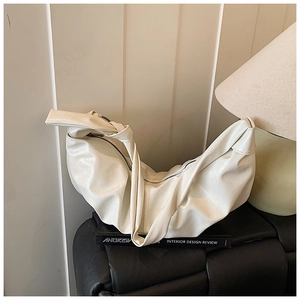 Detailed macro view of the pleated leather texture and knotted strap on the cream cloud bag